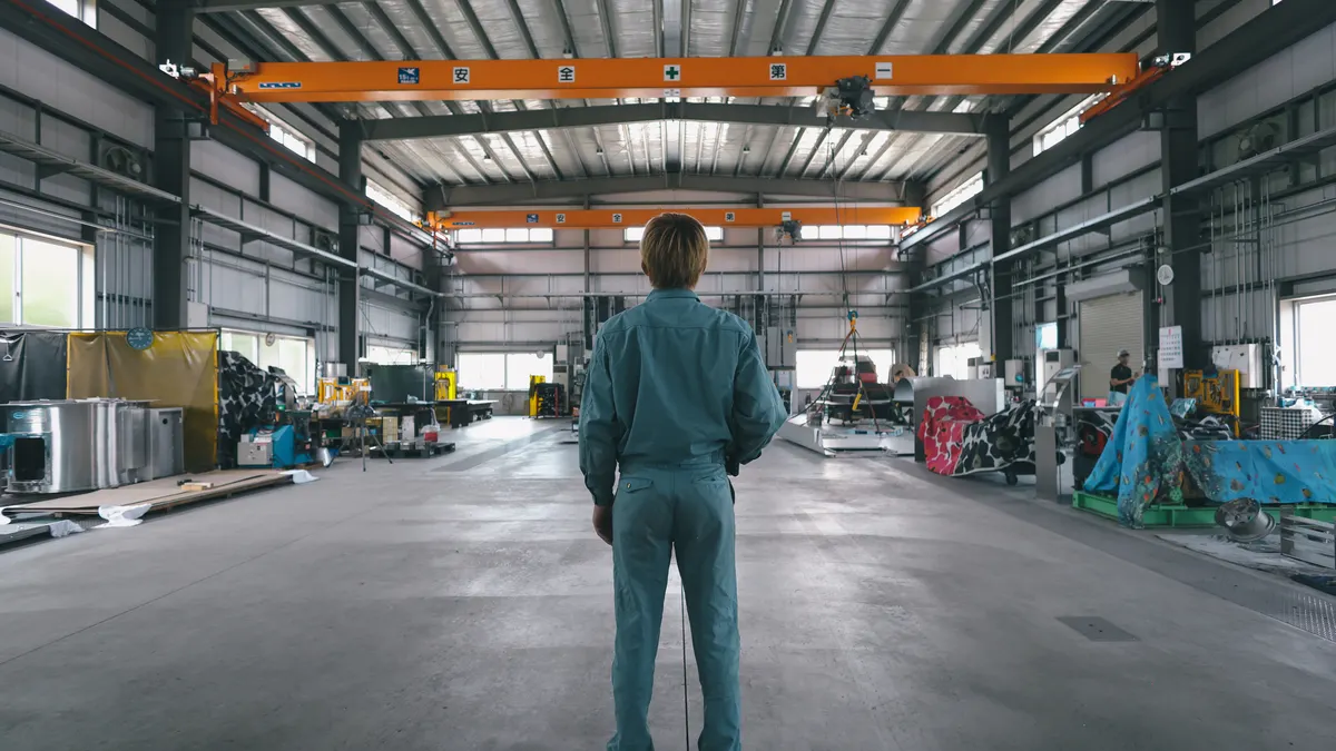 The back of an industrial worker standing in a factory.