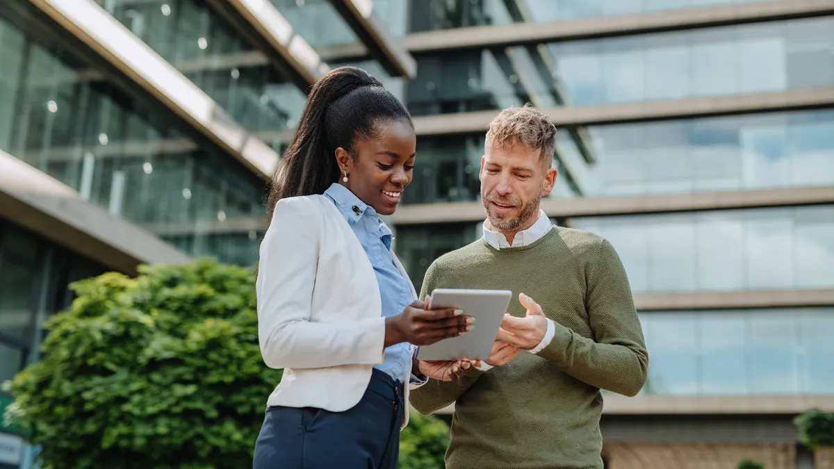 Two professionals collaborating outside on a tablet device.