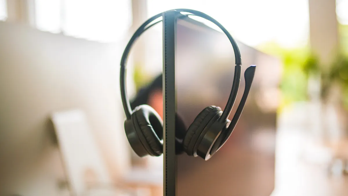 A headset hangs on a laptop