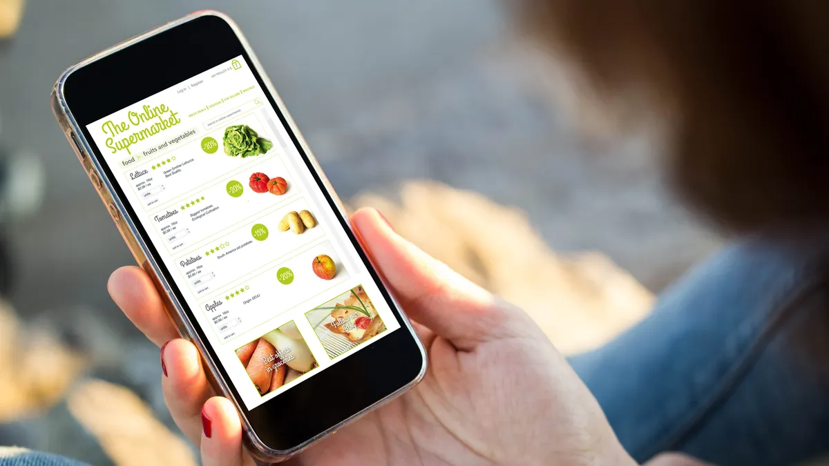 A hand holding a phone with grocery ordering on the screen.
