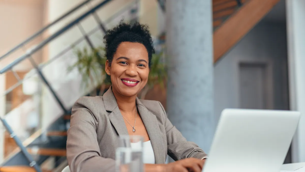 Smiling businesswoman working on laptop in modern office