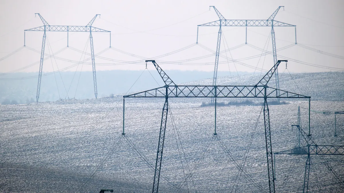 Electric power lines running across a hilly landscape.