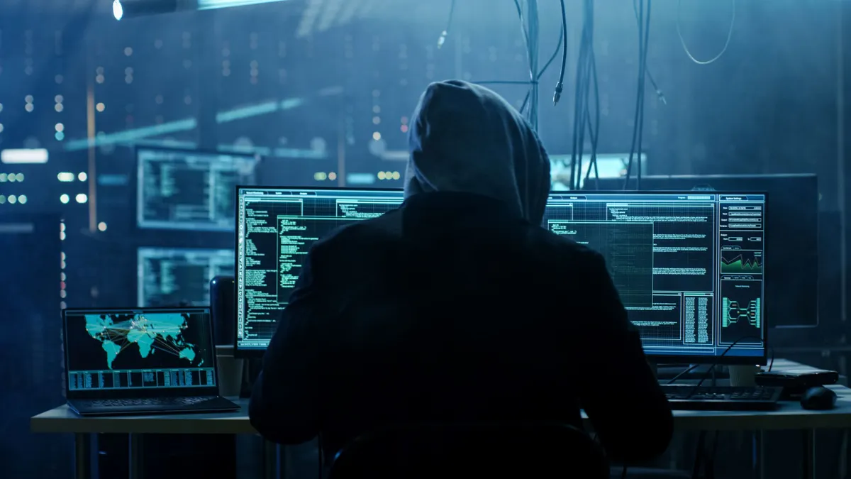 Hooded hacker breaks into an organization's data servers to infect the system with a virus.