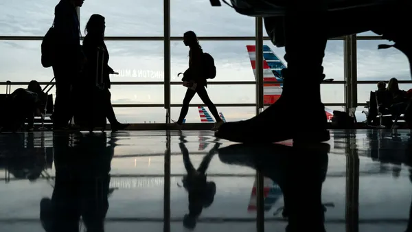 Silhouettes of people walking through an airport terminal.