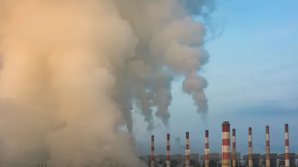 A daytime view of smoke billowing out of a power plant.