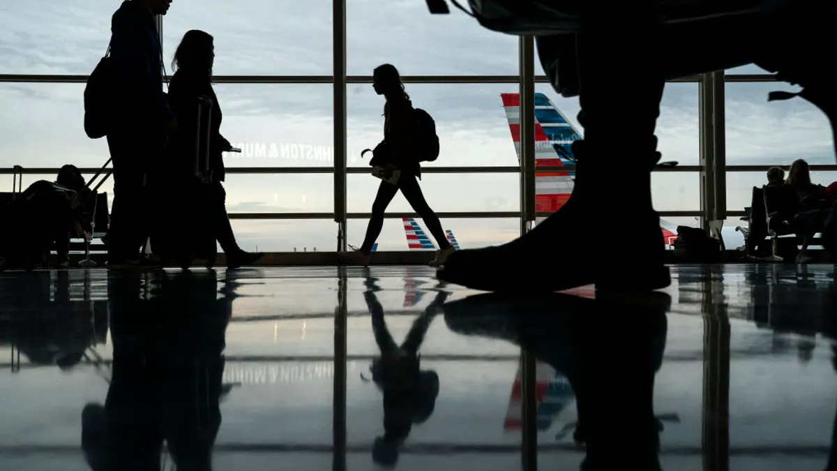 Silhouettes of people walking through an airport terminal.