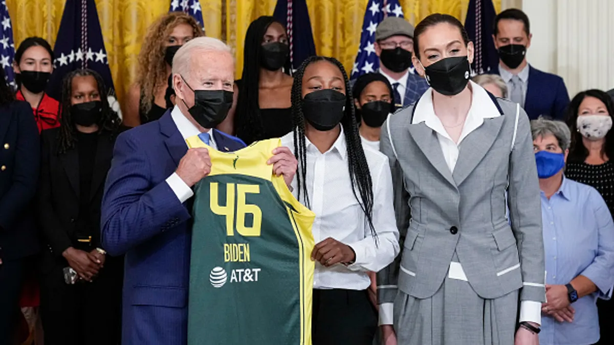 U.S. President Joe Biden accepts a jersey from Seattle Atorm players Jewell Lloyd and Breanna Stewart