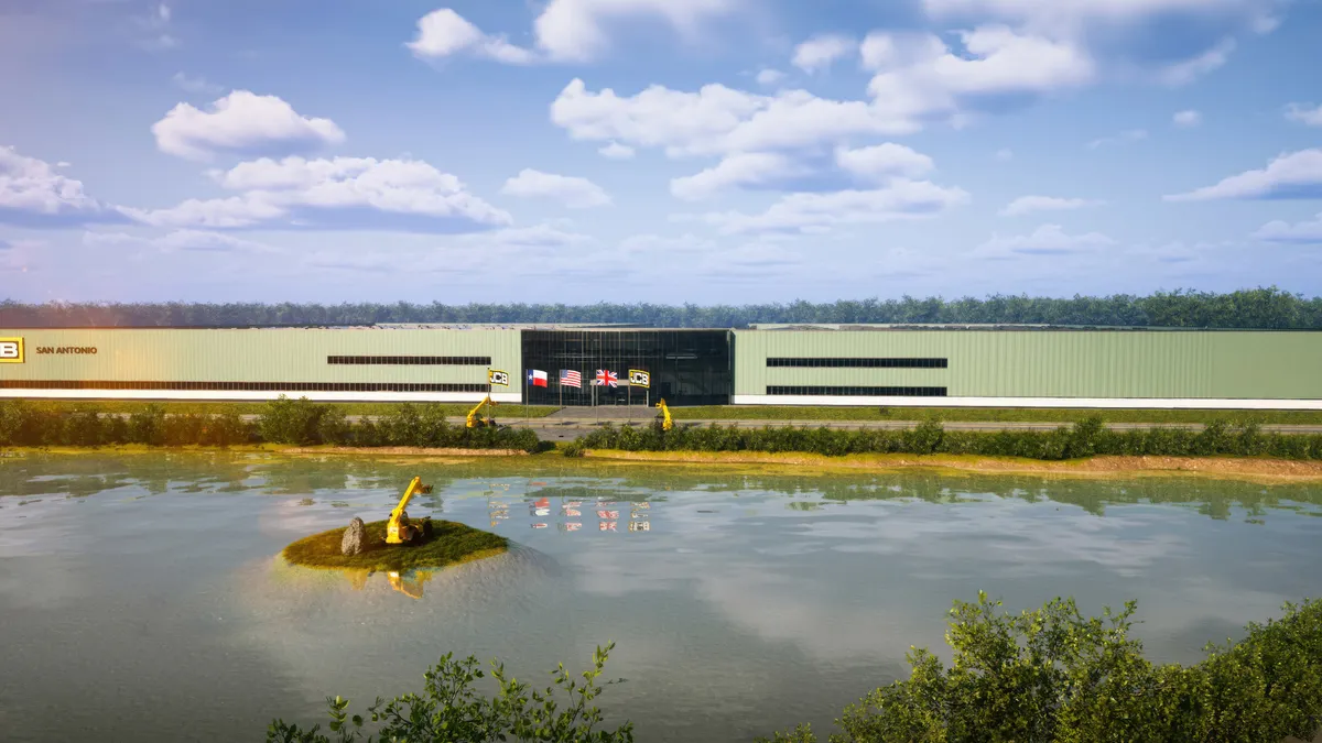 A yellowish building with a body of water in front of it, and a hill with a excavator parked in the middle.