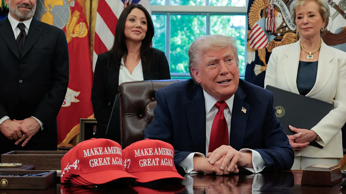 Trump speaks from his desk with officials in the background.