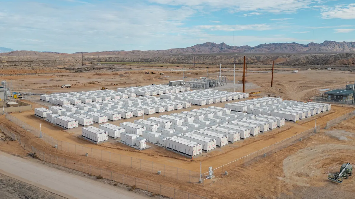 Dozens of large, white containers in a fenced lot in the desert.