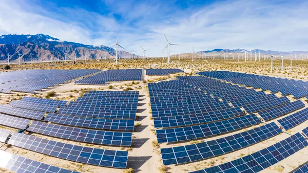 A field of solar panels and windmills in the desert.