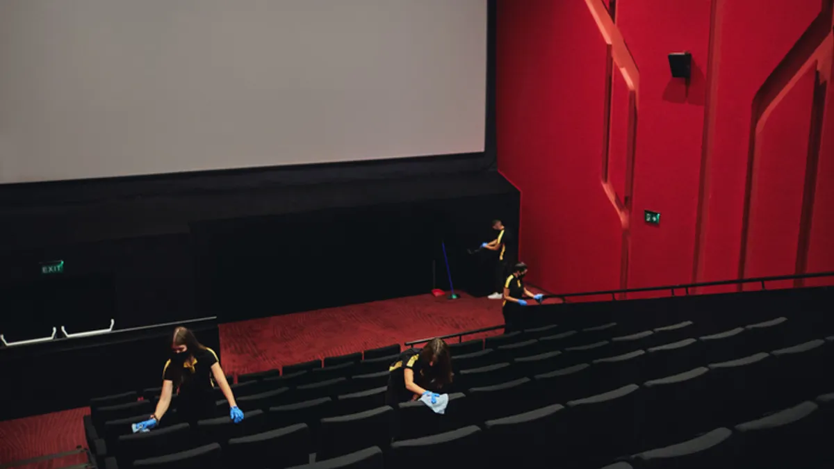 female employees disinfecting movie theater seats before reopening after coronavirus pandemic.