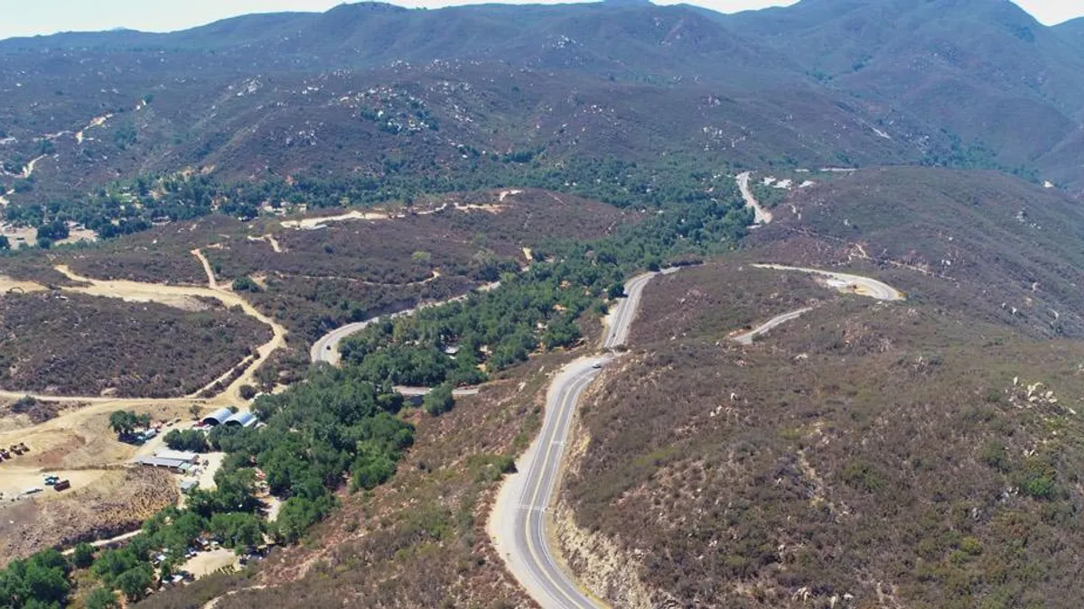 An aerial view shows a winding mountain highway.